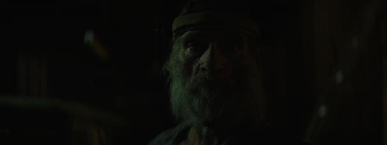 A man sits in the dark under blinking lights