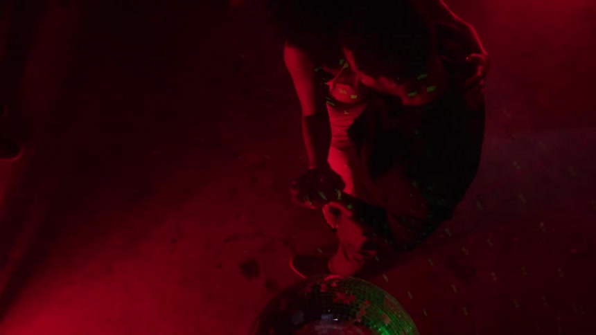 A young couple dancing together under disco lights in a club at night