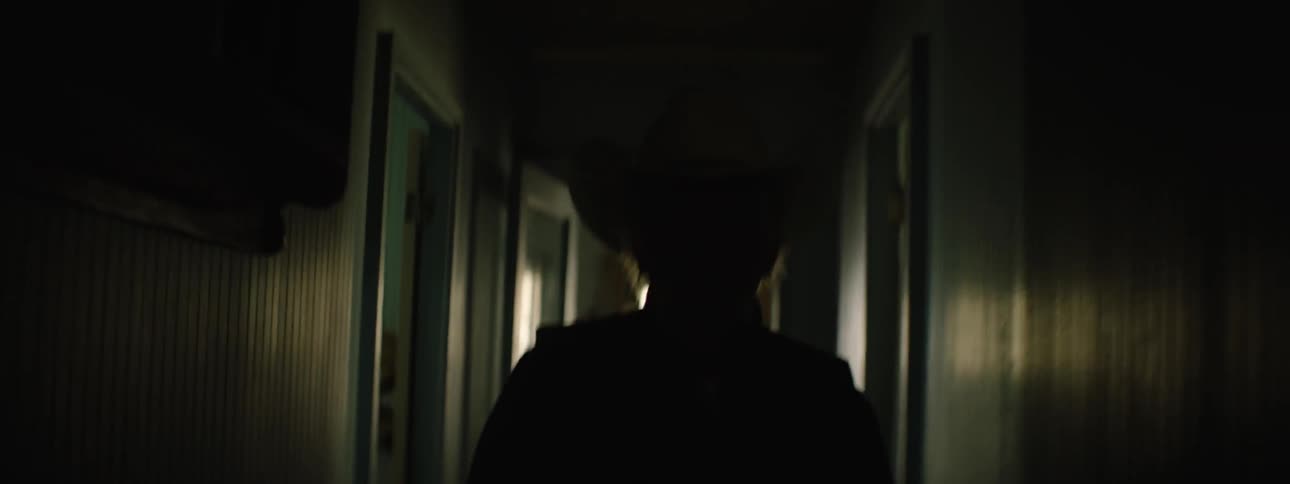 An elderly man in a cowboy hat searches rooms in a house