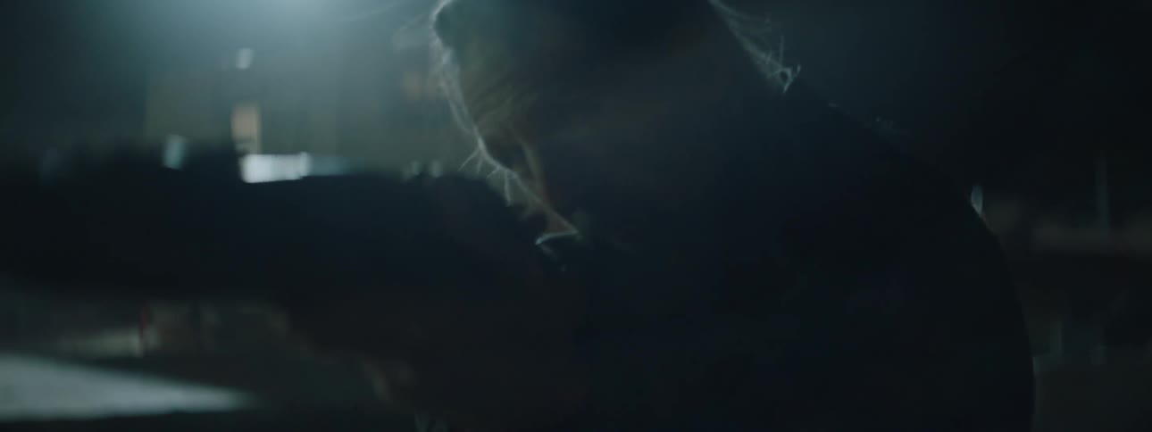 A man is pointing a rifle outside at night