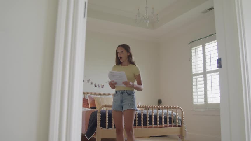 Young girl studies papers while preparing for an exam in a bright bedroom