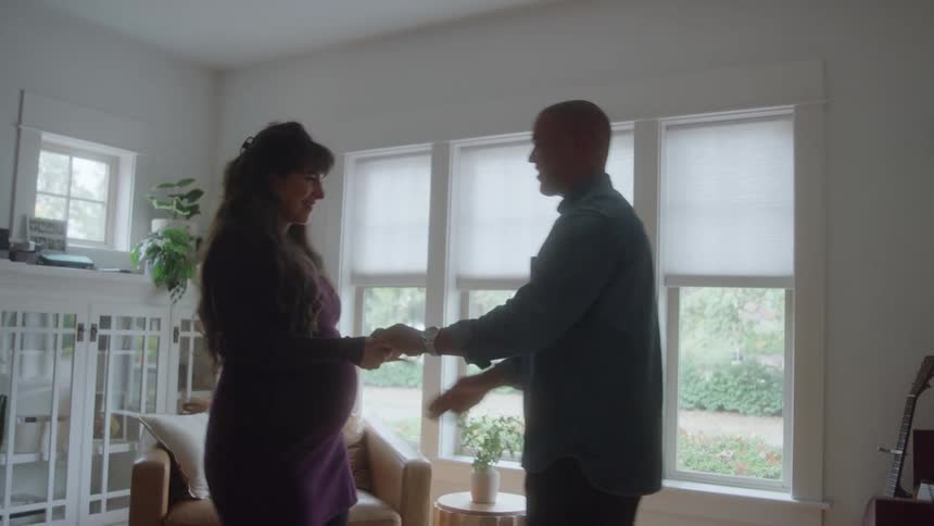 A couple dances and embraces in a modern brightly lit living room