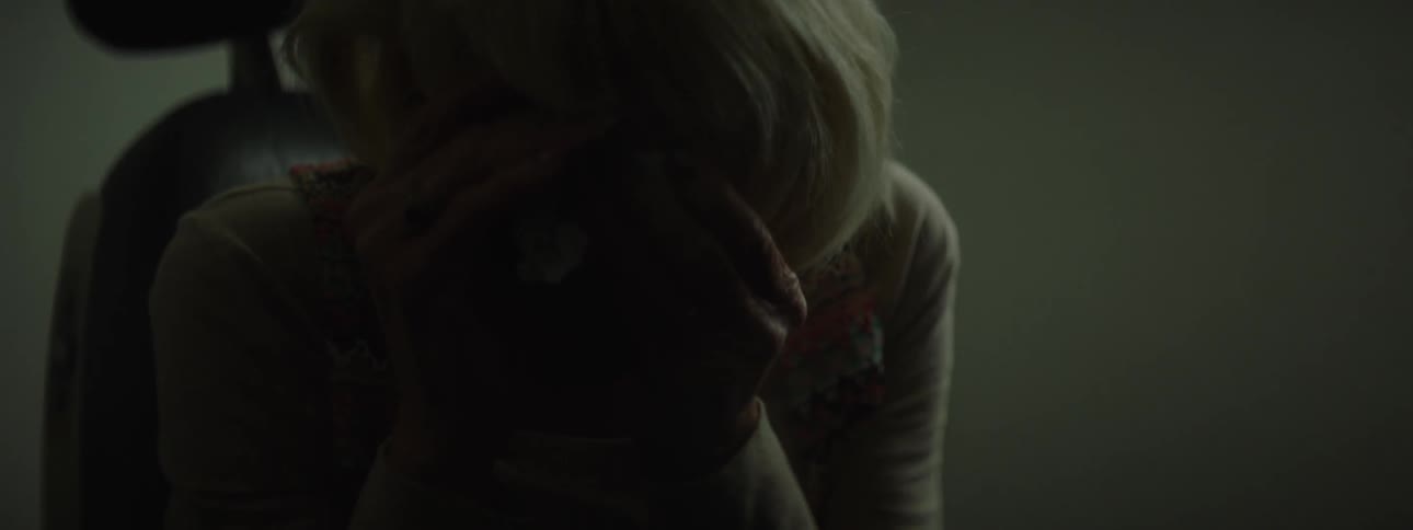 An older woman is sitting in a chair and begins to cry