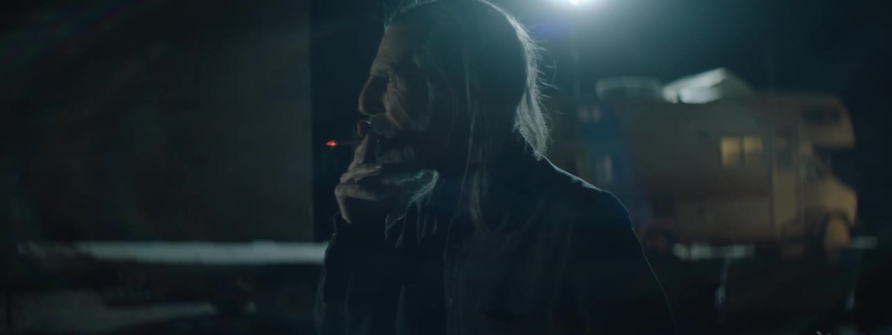A man smokes a cigarette outside at night