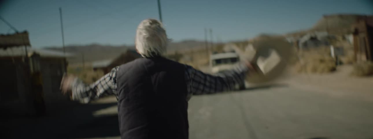 A man crosses the road waving down a vehicle