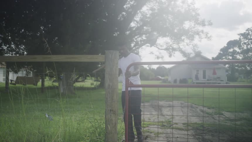 A farmer opens a gate while walking out on a family farm