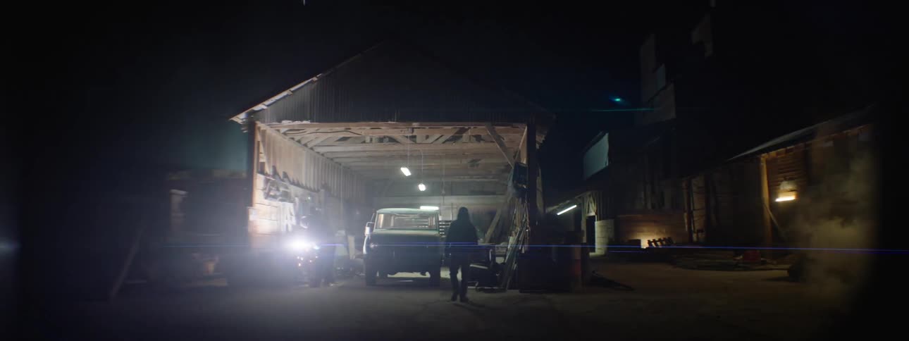 Man welding in open garage while another man walks into garage