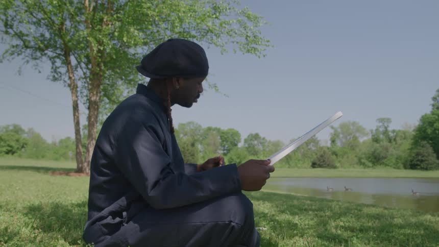 A person painting on a canvas near a peaceful pond