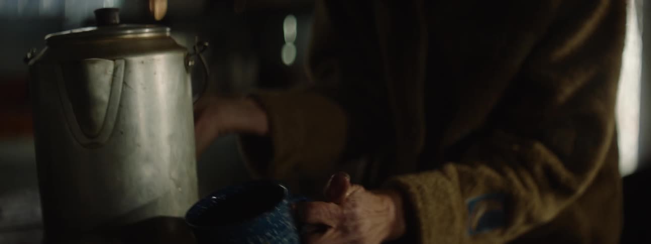 An old woman spills hot coffee on her hands as she pours it from a kettle