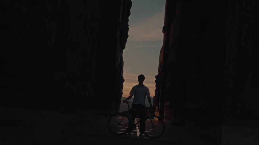 Person with bicycle between mountain walls at sunset