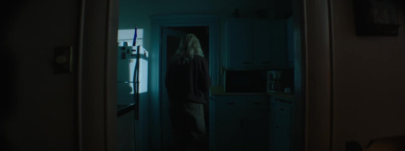 An elder woman looking around in her kitchen and looking out the windows