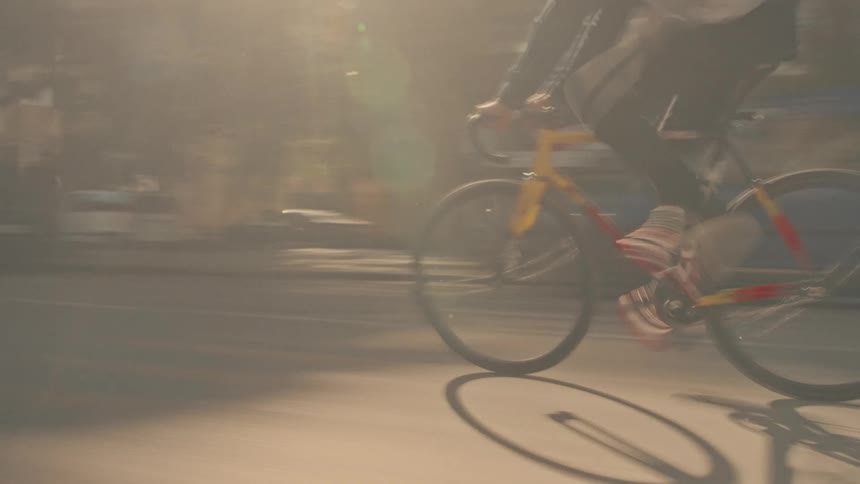 Cyclist rides on an urban street with a yellow and red bicycle