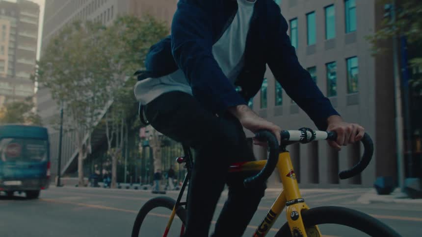 Cyclist rides between buildings in a busy urban area