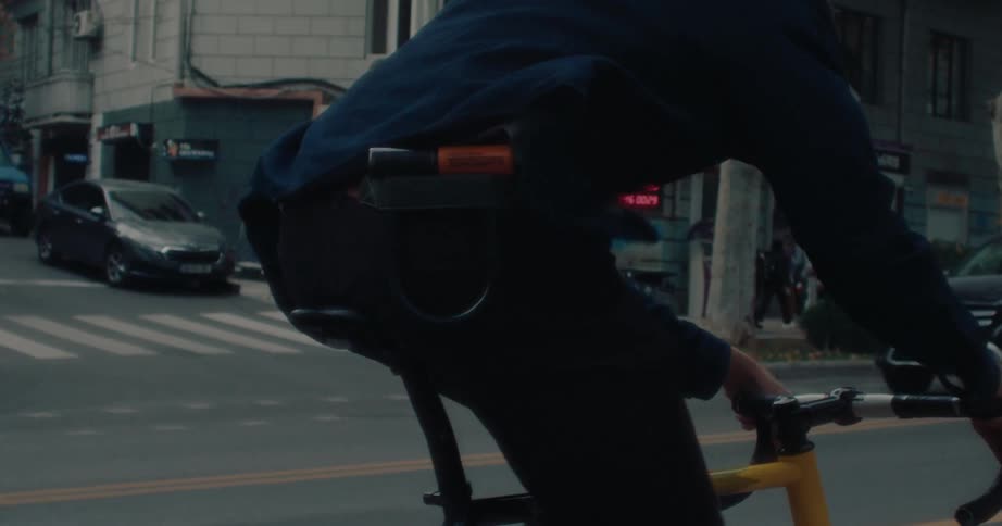 Cyclist rides through a busy street with a lock attached under the bike seat