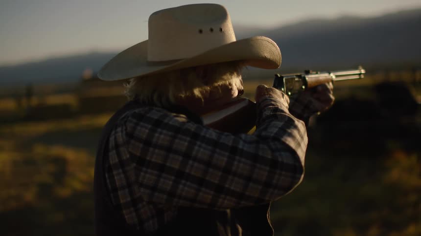 Older man outside pointing a rifle on windy day