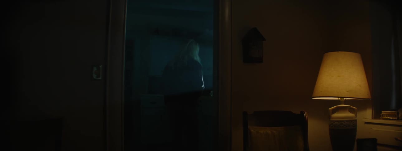 A woman walks into a dark kitchen
