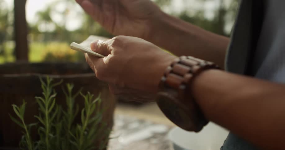 Hands hold pencil over notepad in outdoor setting with grass and trees in the background