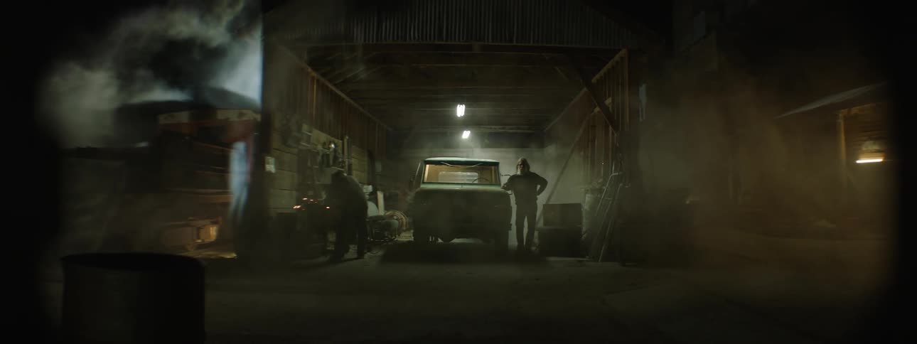 Wind blows dirt through a barn with people working