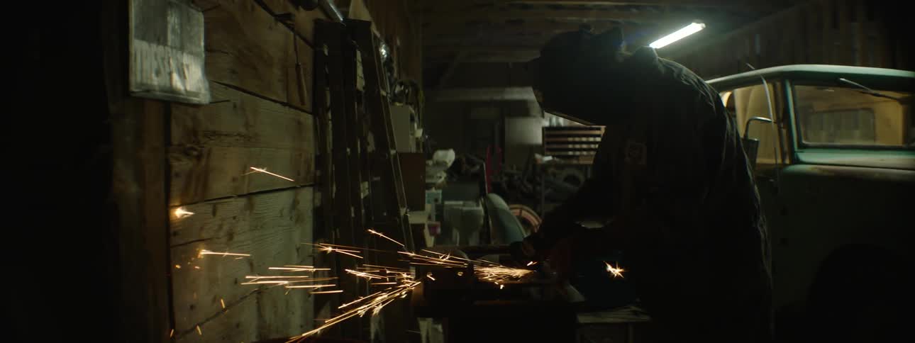Man wearing welding helmet is welding in a shop
