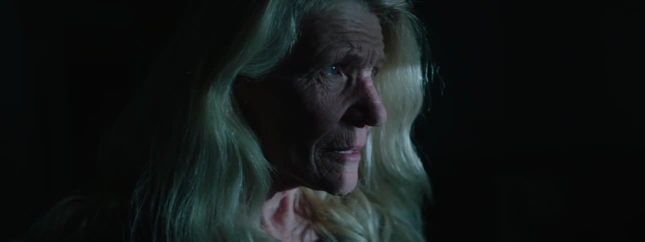 An elder woman looking around in a dark space