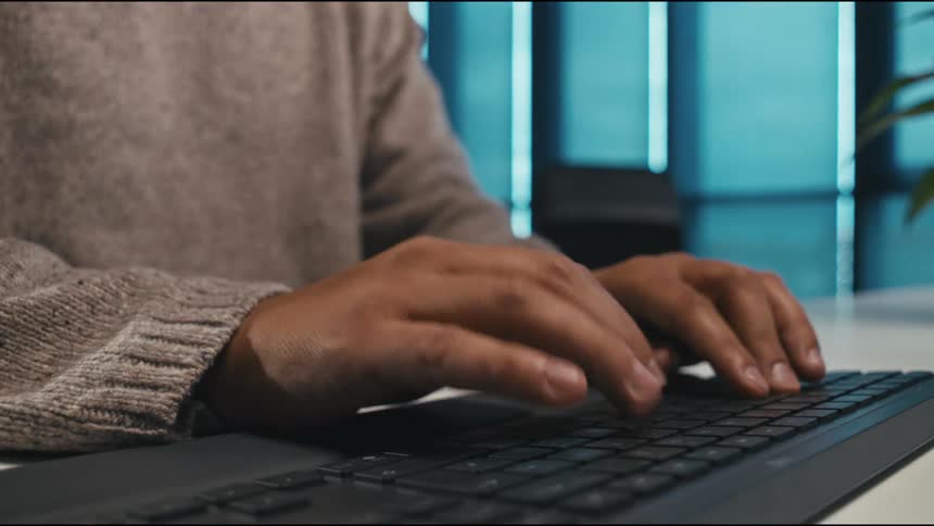 The man is typing on his keyboard in the office
