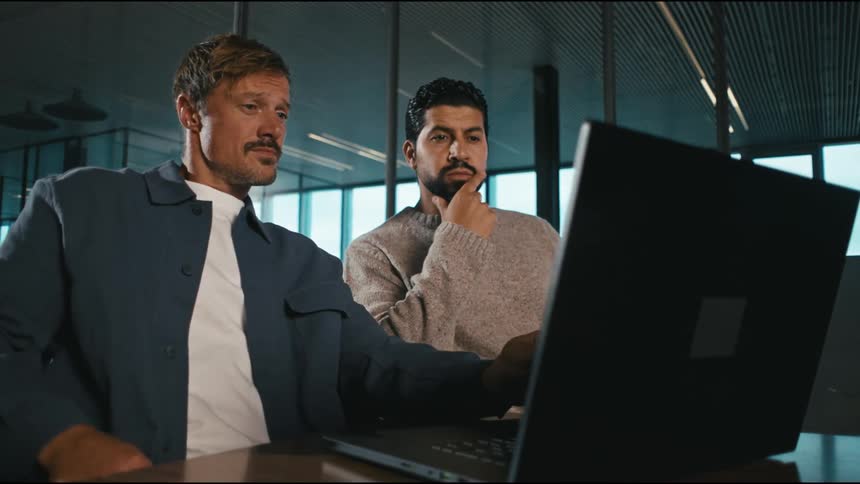 A couple men looking at a computer screen