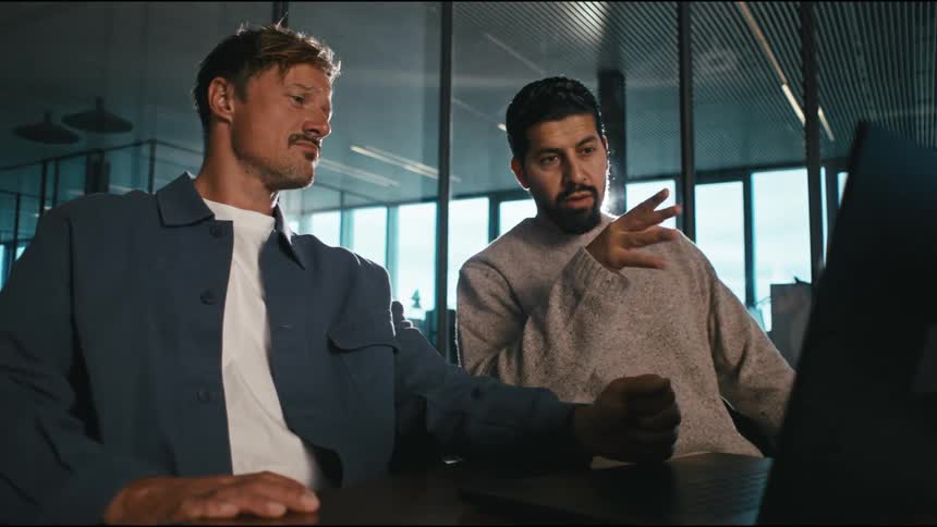 two colleagues discus something at a computer screen