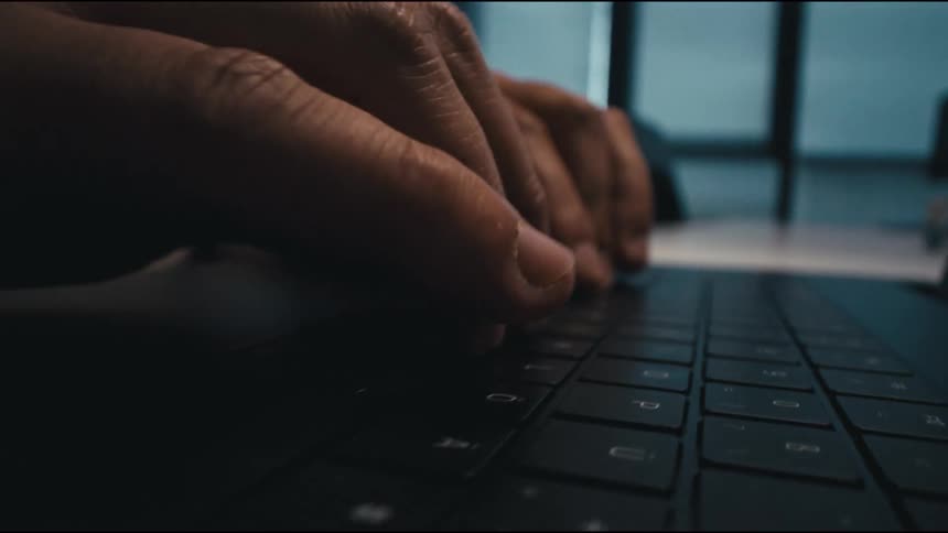 a man is typing concentrated on a laptop at his desk in the office
