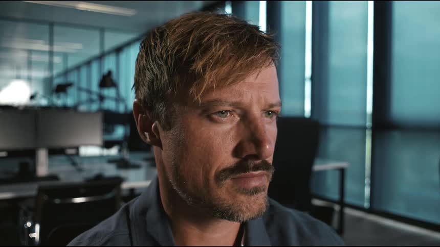 Close up portrait of a man working in an office, looking at screens, typing