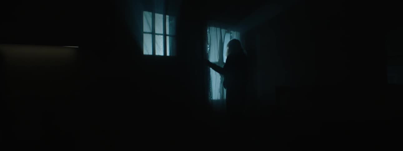 A woman looks out a window at flashing nights