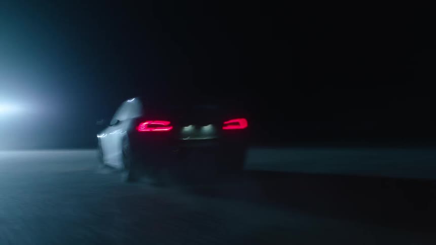 A car drives towards a bright light at night
