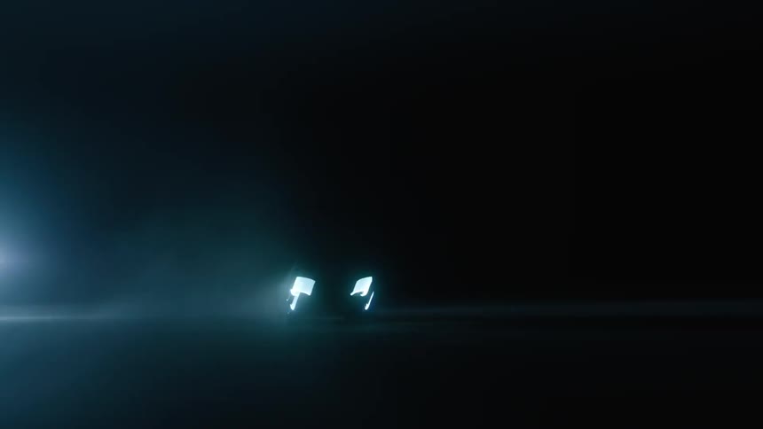 A car drives with its headlights on at night
