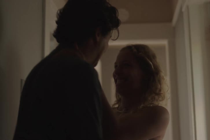 A young couple romantically enter the bedroom together from the corridor