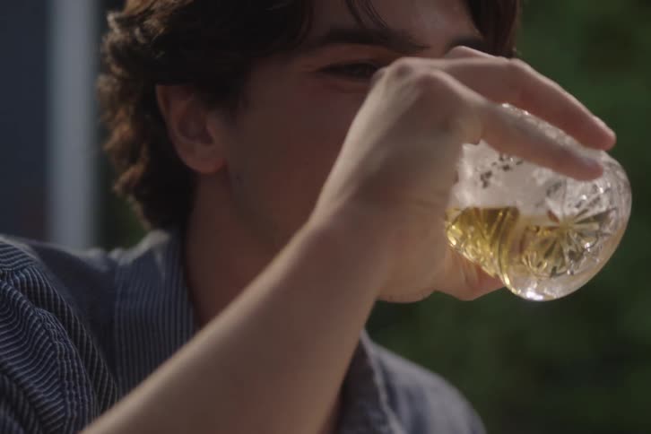 The teenager laughs and drinks