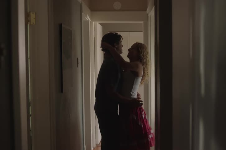 The couple hug and kiss in the hall before going in a room