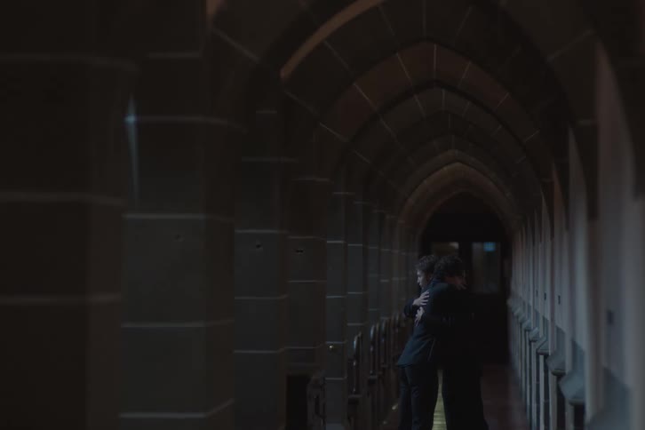 Two men embracing in an arched hallway