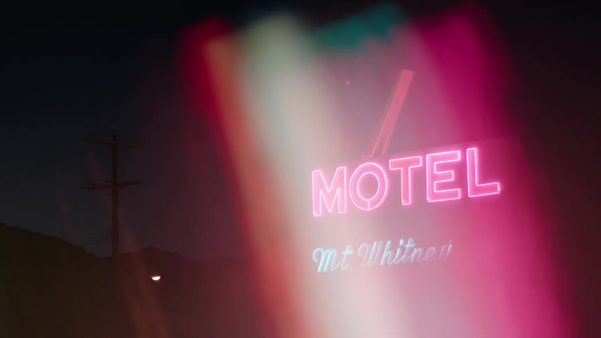 A view of a motel sign with some rainbow thing going on at night