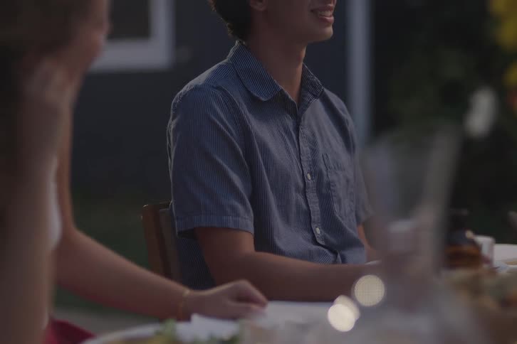 A young female and a young male sit at a dining table laughing and smiling