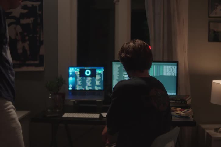 Two nervous teenager boys operating a computer indoors during night time