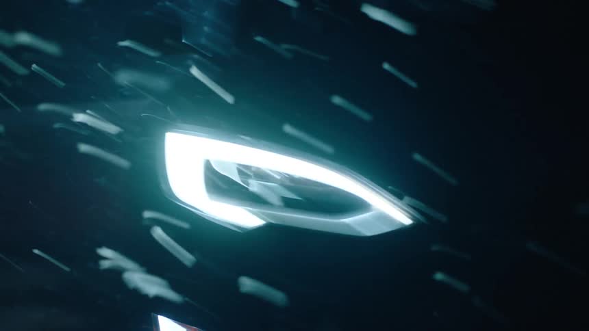 A car drives at night with its headlights on