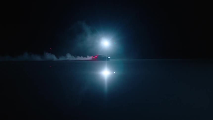 A car drives by a bright light at night