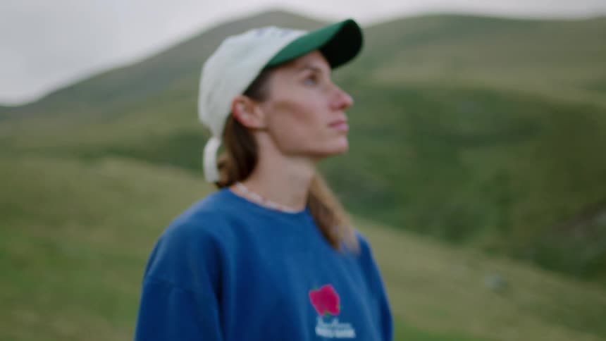 Person wearing a light cap and blue sweatshirt looking at the mountain landscape