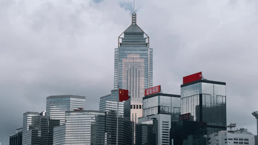 Modern skyscrapers of hong kong with the chinese flag waving under a cloudy sky