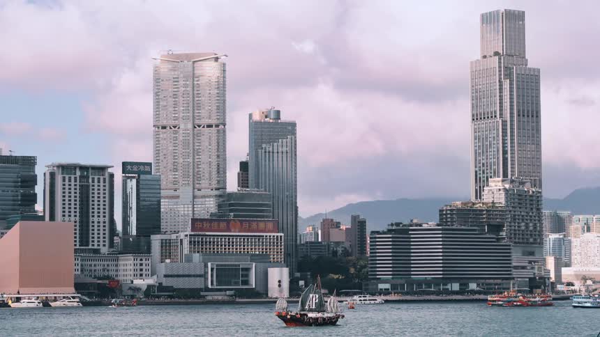 Sailing boat gliding in front of modern skyscrapers by the seaside