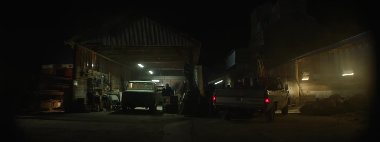 An old pickup truck drives next to a garage