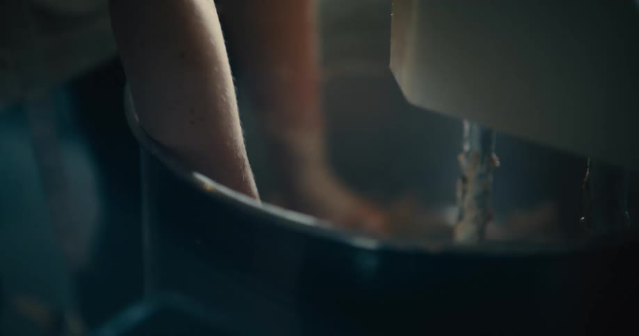 A baker removes dough from an industrial mixer
