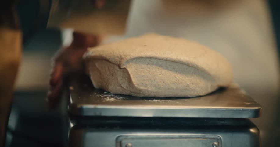 The baker weights dough on a scale