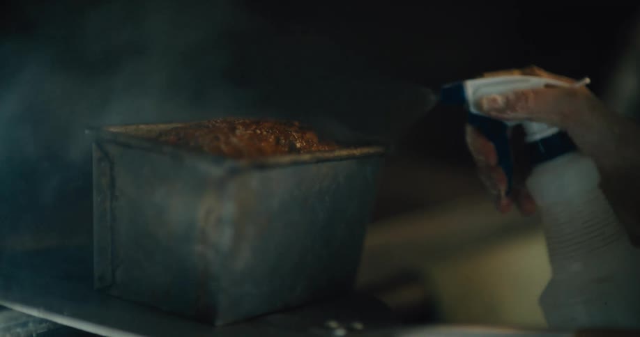 Bread baking in a metal pan while being sprayed with water