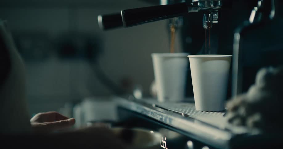 Coffee being brewed in a professional machine and served in disposable cups