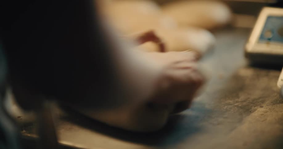 Close up of a young woman kneading baking dough on a tabletop